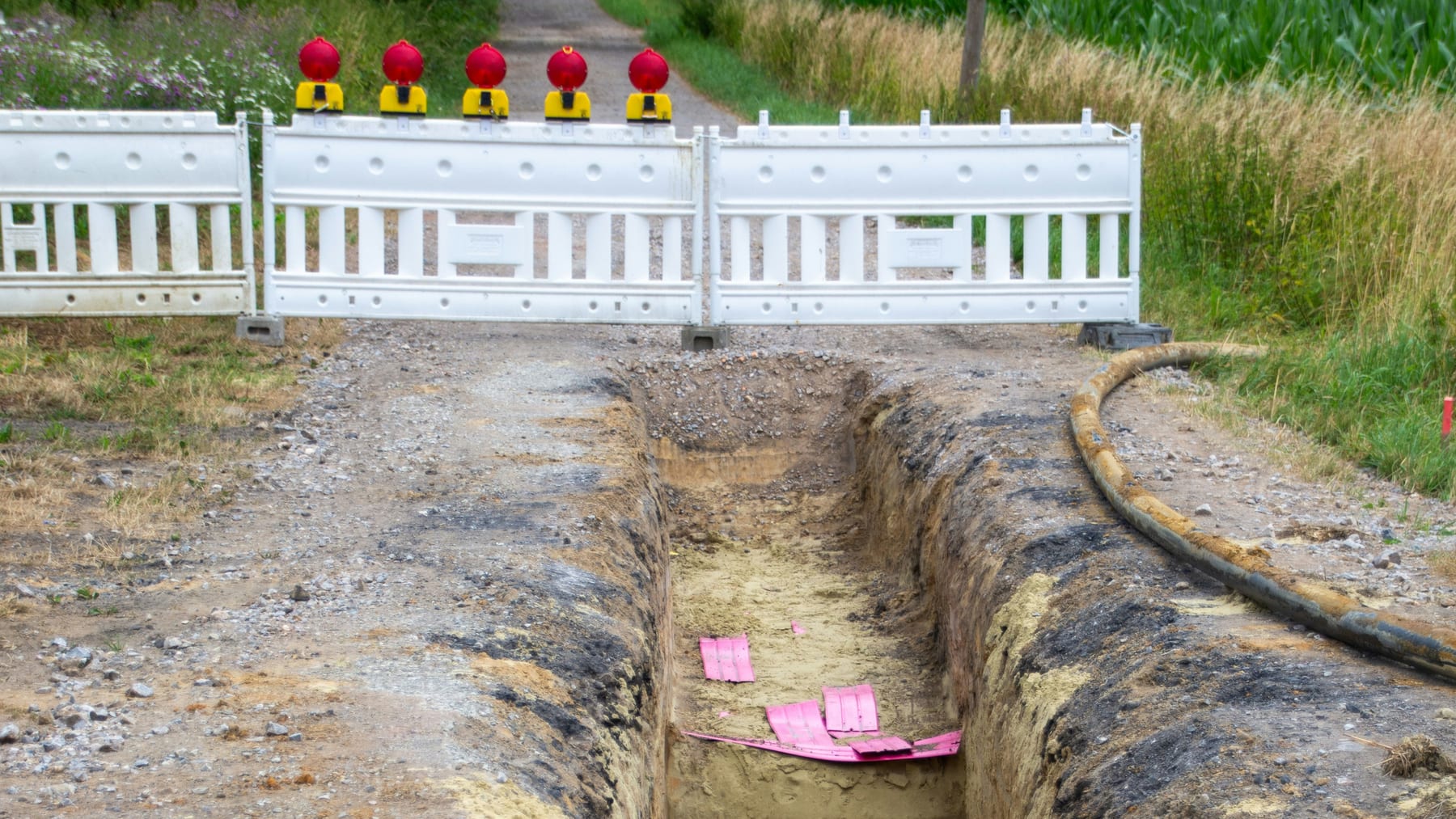 Freshly dug cable trench on a farm track with warning tape