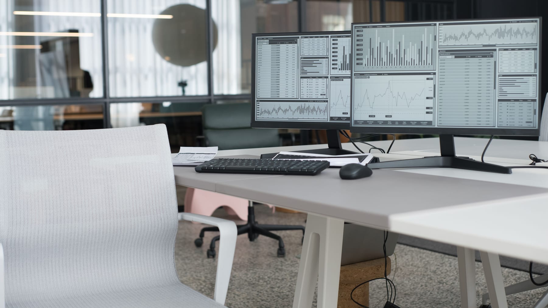 Office workstation with two monitors full of charts and tables